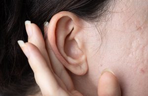 A lady holding her ear.